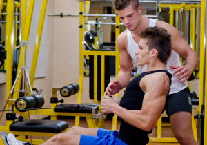 Personal trainer helping client in gym